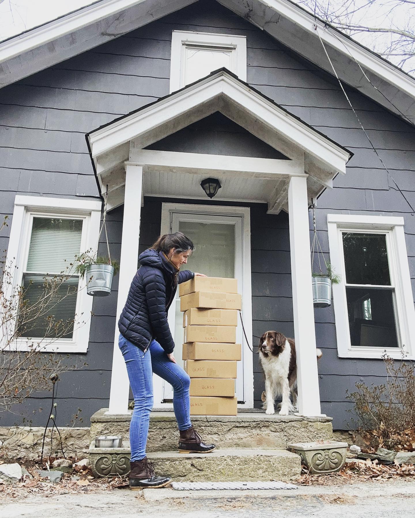 Elaine carrying packages with Balu watching from the front porch